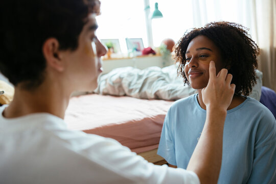 Man applying eye patches to female friend at home