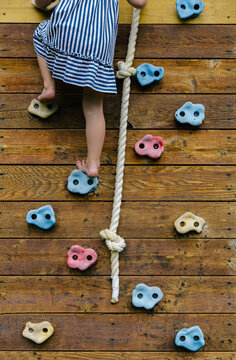 Child at Play climbing wall with rope on swing set background 