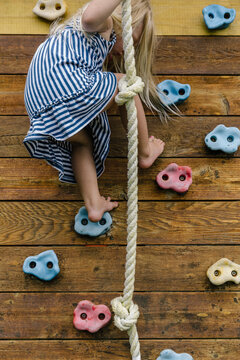 Child at Play climbing wall with rope on swing set made of wood