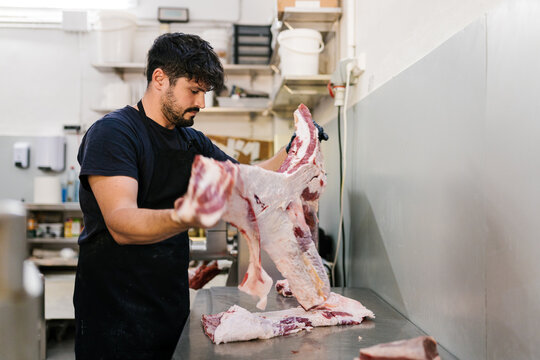 Man cutting fresh beef in kitchen