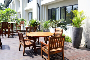 Stylish dining room with design craft wooden table, chairs, furniture, lots of plants, windows, poster maps and elegant accessories in modern home decor.  wooden table and chairs on the balcony