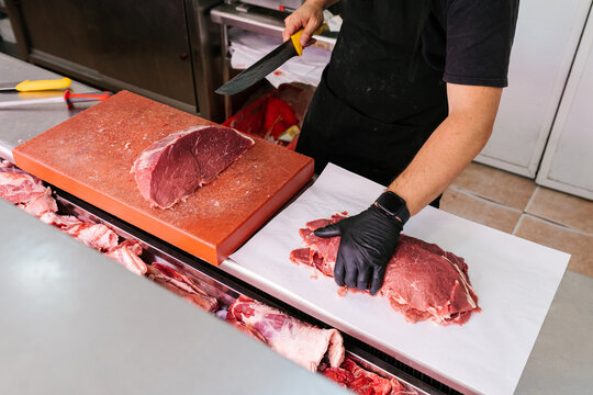 Crop worker cutting raw meat in butchery shop