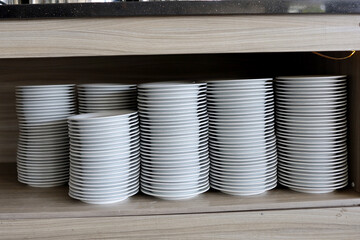 pile of white ceramic plates on a shelf.  all you can eat restaurant and buffet