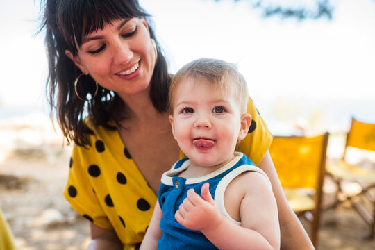 Cute baby with tongue out and smiling mother 