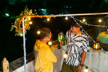 Diversity Asian people friends drinking beer and talking together during having dinner party at outdoor rooftop. Man, woman and LGBTQ person enjoy celebrating holiday meeting party on summer vacation.