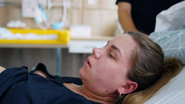 Caucasian woman delivering a baby. Lady is trying to push her child and her face becomes red. Close up.