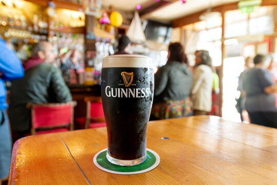 General view of a full pint of Guinness Irish dry stout Beer in a colorful busy pub in the city of Cobh, Ireland, on July 24 2023.
