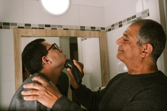 Grandfather Guides Teenager with Intellectual Disabilities Shaving.