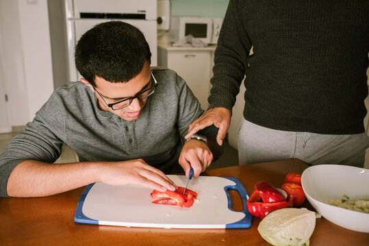 Guiding Hand: Grandfather Assisting Boy with Vegetable Cutting.