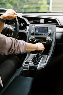 middle aged woman in car putting the vehicle into gear to drive