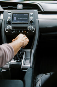 middle aged woman in car putting the vehicle into gear to drive