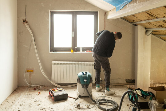 Man installs electrical wiring through the room