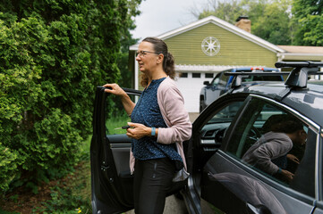 middle aged woman entering her sedan gray car to drive somewhere