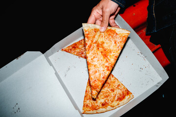 man taking a slice of cheese pizza