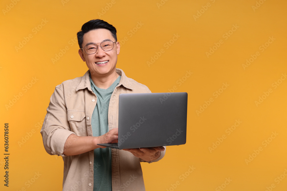 Poster Happy man with laptop on yellow background, space for text