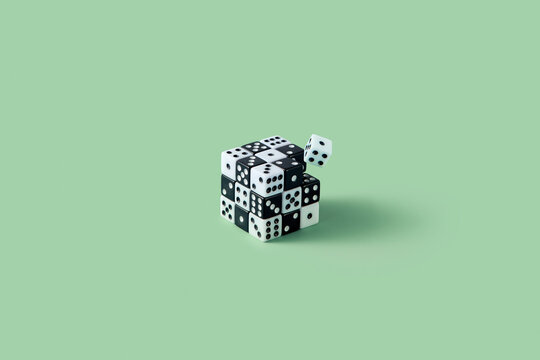 Cube made of black and white dice against green background.