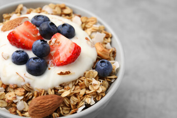 Tasty granola, yogurt and fresh berries in bowl on light grey table, closeup with space for text. Healthy breakfast