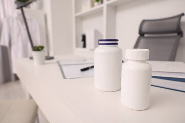 Plastic medical bottles on white table, space for text. Doctor's workplace