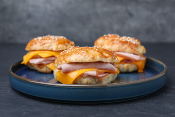 Delicious bagels with ham and cheese on black table, closeup