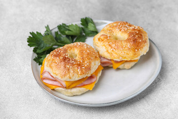 Delicious bagels with ham and cheese on light table