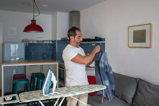 young man ironing clothes at home