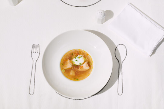 chicken soup in a white plate on a white tablecloth