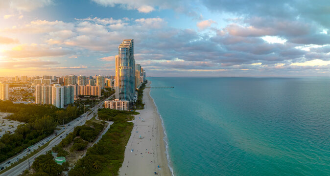 Expensive highrise hotels and condos over sandy beachfront on Atlantic ocean shore in Sunny Isles Beach city at sunset. American tourism infrastructure in southern Florida