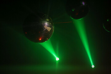 Backlit disco ball against green light at party with copy space