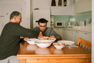 Grandfather and Grandson Have Dinner Together Smiling and Talking.