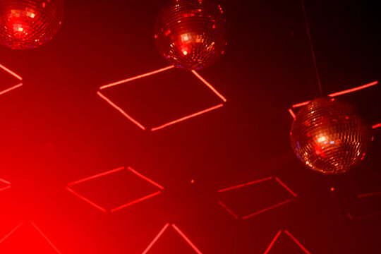 Mirrorballs + light squares reflecting red light at party: copy space