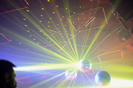 Mirrorball reflecting colorful rays of light at nightclub party