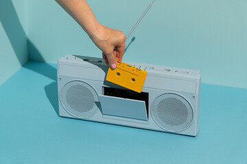 Woman inserting cassette into colorful boombox. Music concept.
