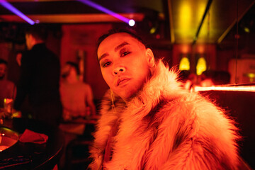 Flamboyant Individual Strikes a Pose in a Dimly Lit, Red-Hued Bar