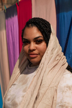 
Braided-hair British girl stands in front of colorful Moroccan scarf
