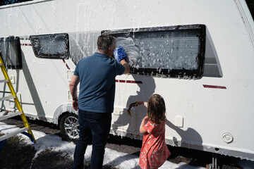 Man with kid washing the van 