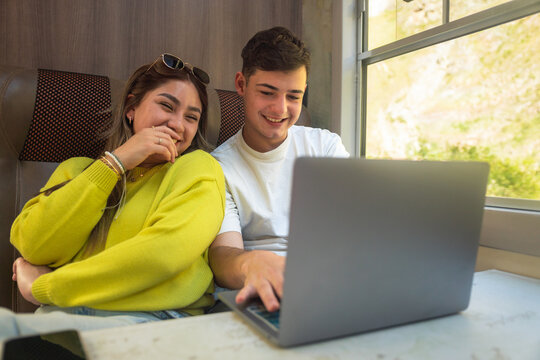 Young couple using laptop while traveling by train