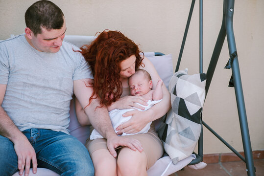 Young Couple on Bench, Gazed Fondly at Their Baby Boy.