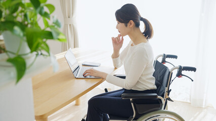 車椅子に乗るパソコンを使う女性