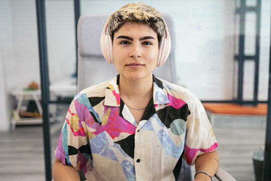Non-binary person with headphones on a video call in the office