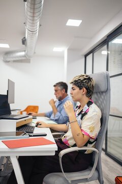 Young non-binary person working with laptop in the office