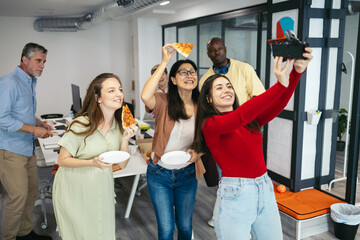 Team of workers taking a selfie in the office while having a party