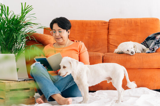 Woman at home reading a book with her pets.