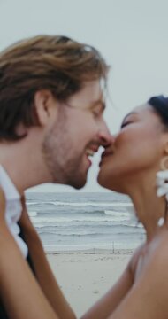 The bride and groom rub their noses and kiss standing on the seashore
