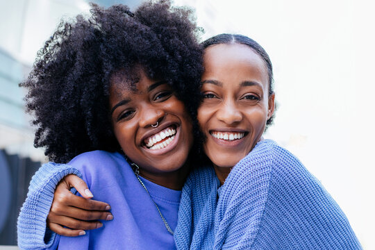 Delighted black girlfriends resting on bench