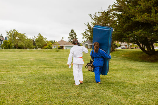 Judokas with mat walking by the park