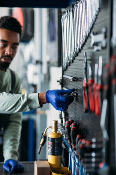 Car Service Worker Taking Tools from Wall