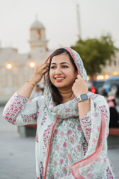 Positive Indian woman adjusting ornamental headscarf