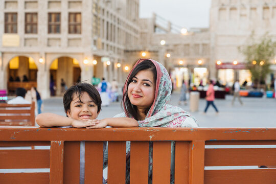 Happy woman resting on bench with son