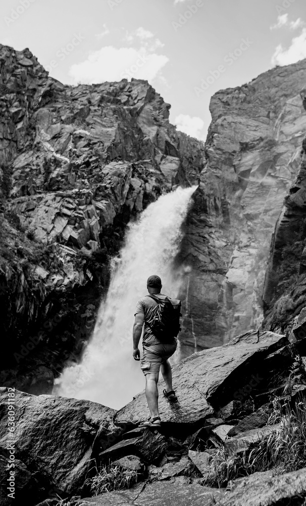 Wall mural hiker at waterfall. black and white toned image