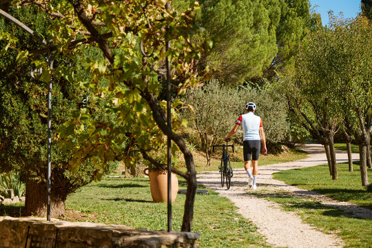 Male Cyclist walking up driveway of European house